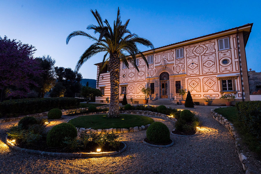 An exterior view of Villa Capponi shows its symmetrical graffito patterns adorn its cream plaster ele